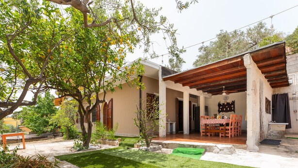 Ein Haus mit überdachter Terrasse, Rasen und Essbereich.