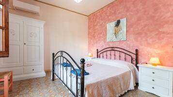 A bedroom with a bed, a nightstand, a dresser, a wardrobe, and a painting on the wall.