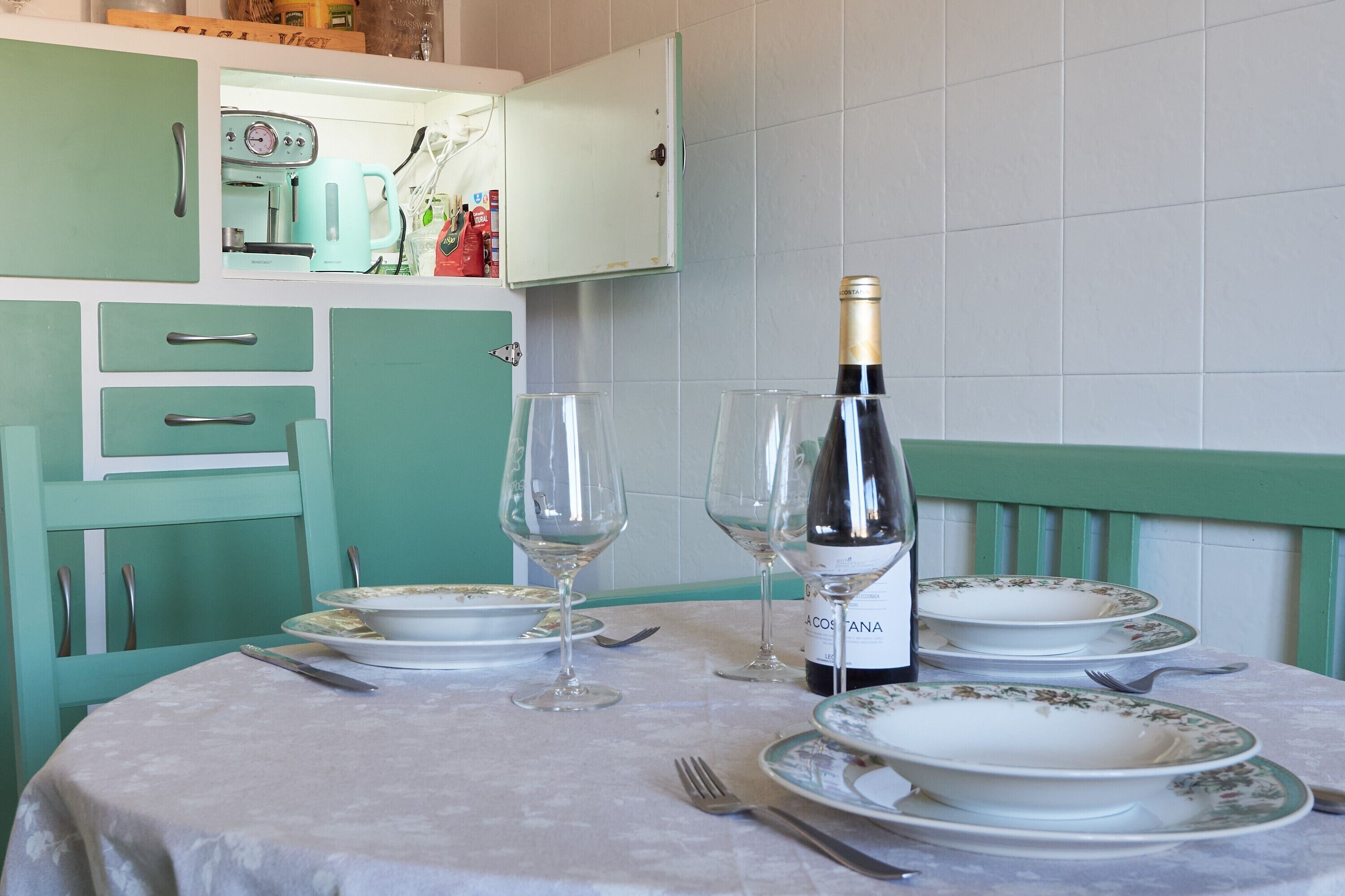A dining table set with plates, wine glasses, and a bottle of wine.