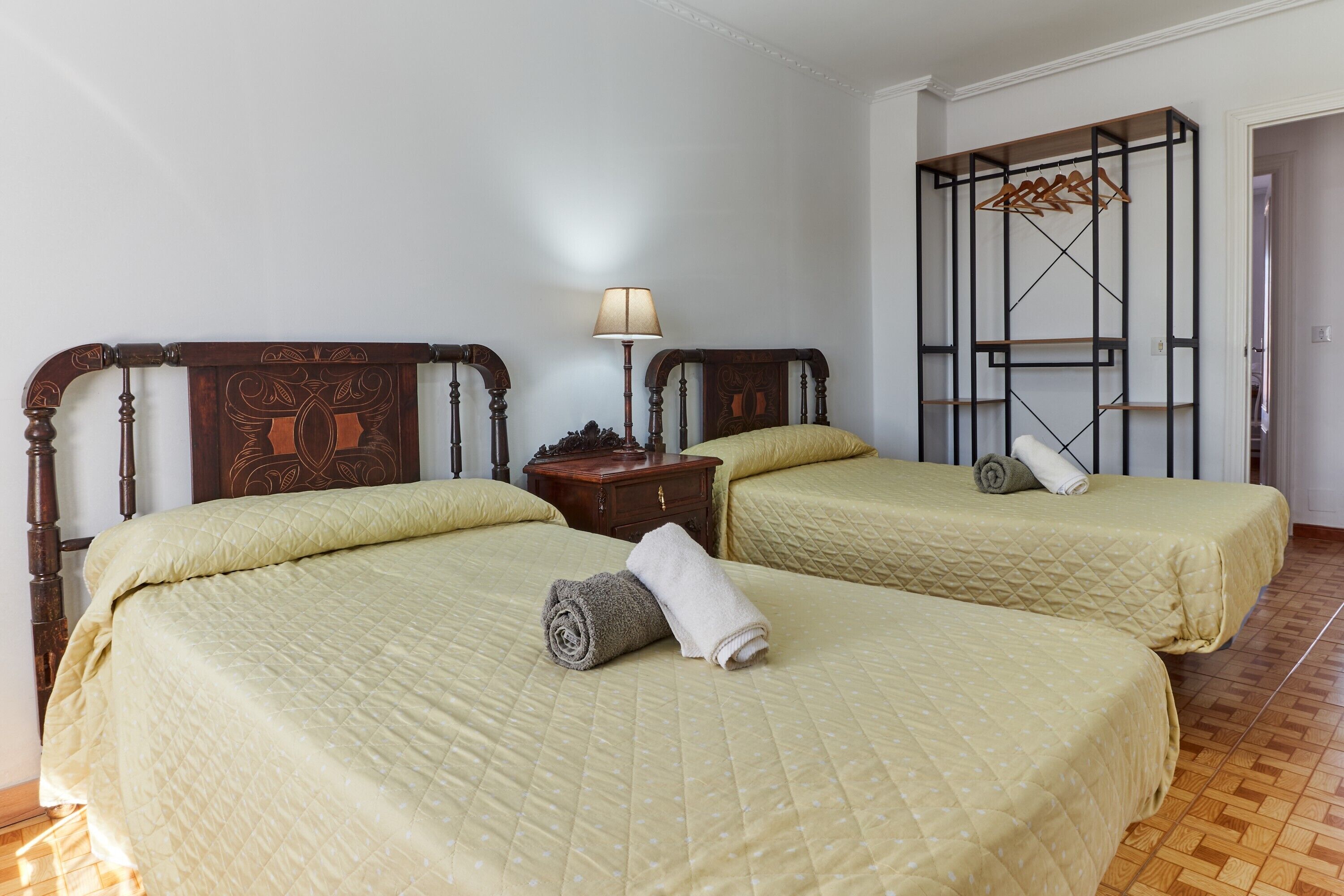 Une chambre avec deux lits, une table de chevet, une lampe et une armoire.