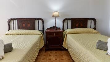 Een kamer met twee bedden, een nachtkastje, een lamp en een houten vloer.