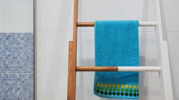 A bathroom with a wooden towel rack holding a blue towel with a green and yellow pattern.