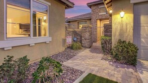 A residential building with a stone facade, a paved entrance, and a well-lit exterior. - Secluded Private Golf/Pool Home With Game Room (Indio)
