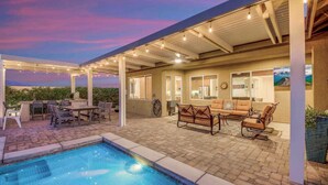 A covered outdoor area with a pool, patio furniture, and a seating area with a sofa and chairs. - Secluded Private Golf/Pool Home With Game Room (Indio)