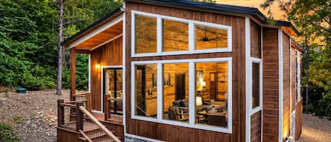 Una cabaña moderna de troncos con base de piedra, ventanas amplias y una terraza de madera.