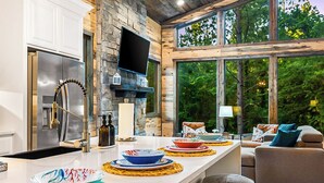 Une cuisine moderne dotée d’un grand îlot central, d’appareils électroménagers en acier inoxydable et d’un mur décoratif en pierre.