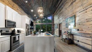 Une cuisine moderne dotée d’un îlot central, d’appareils électroménagers en acier inoxydable et d’un plafond en bois.