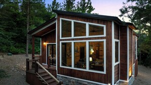 Une cabane avec des fondations en pierre, un revêtement extérieur en bois et un escalier menant à une véranda.