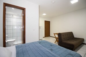 Een slaapkamer met een bed, een houten stoel, een kledingkast en een deur naar een badkamer.