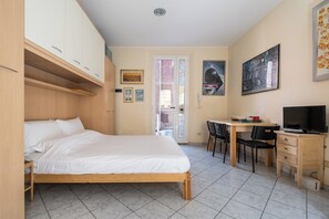 Una camera da letto con un letto, una scrivania, una sedia e un televisore.