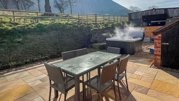 An outdoor patio with a hot tub, wicker furniture, and a view of a mountain. - 3 bedroom accommodation in Church Stretton (Church Stretton)