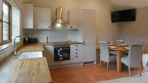 A kitchen with a wooden countertop, an oven, a sink, and a dining area with chairs and a table. - 3 bedroom accommodation in Church Stretton (Church Stretton)