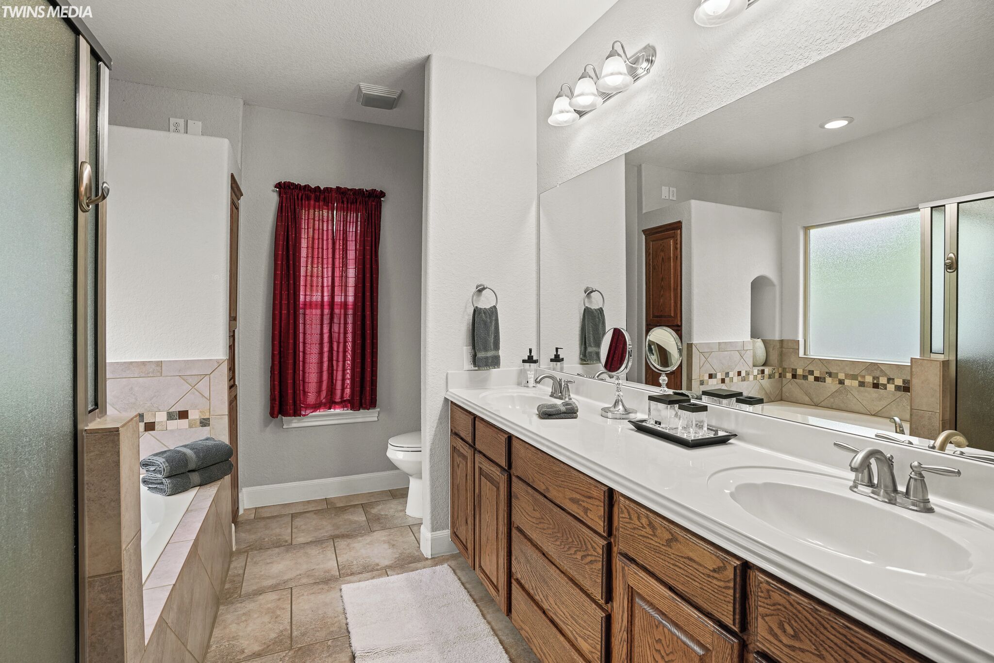 A modern bathroom with a large mirror, two sinks, and a bathtub.