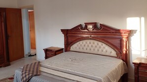 Un dormitorio con cama de madera, una mesita de noche y un ventilador de techo.