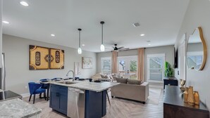 A modern kitchen with a central island, built-in appliances, and pendant lighting.