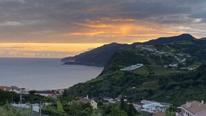 A coastal landscape with a view of the sea and a hilly area with buildings.