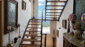 A staircase with a view of the outdoors, surrounded by framed artwork and decorative items.