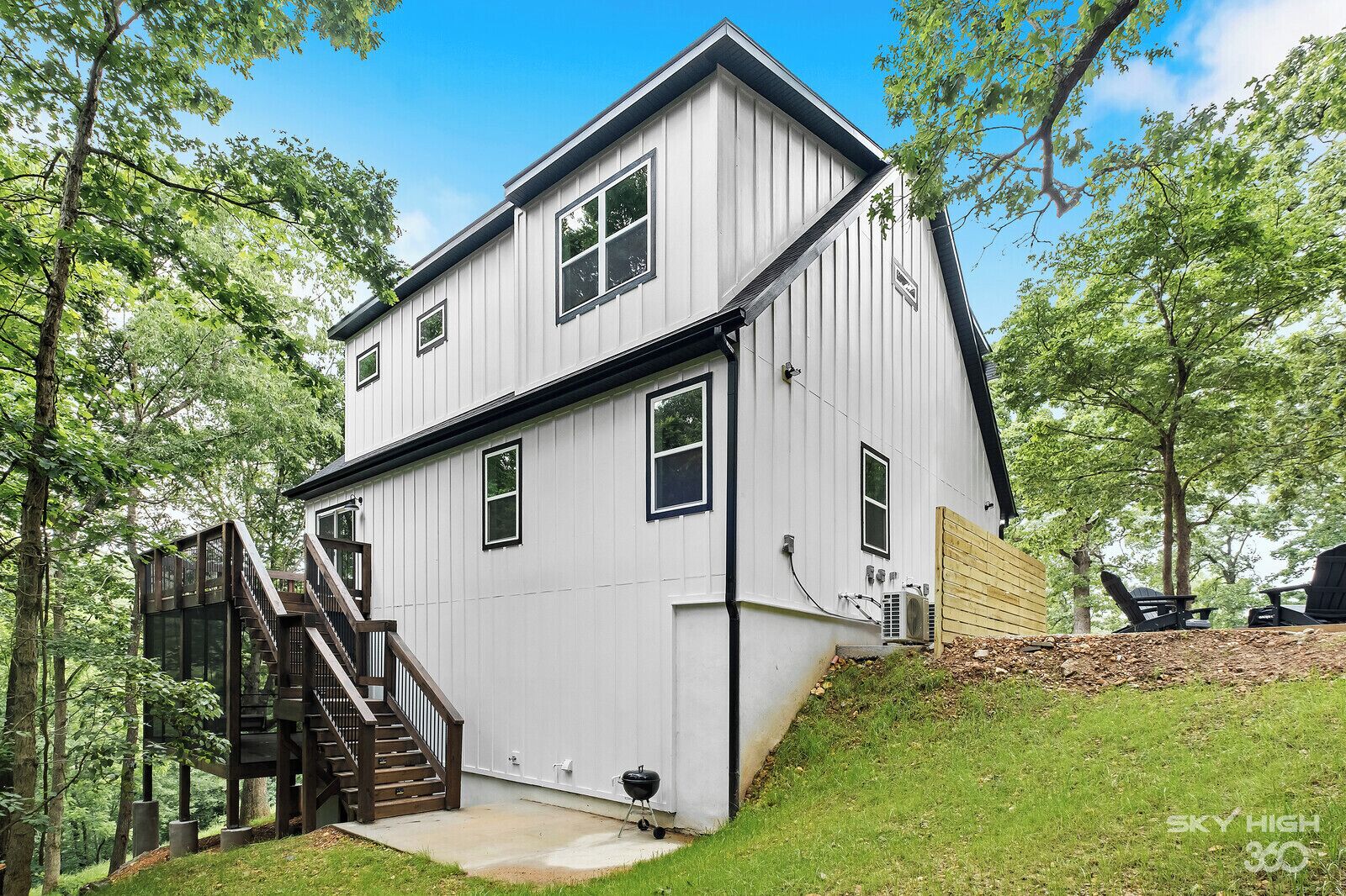 A two-story house with a wooden deck and a staircase leading to the upper floor.