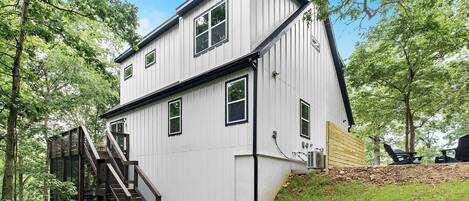 A two-story house with a wooden deck and a staircase leading to the upper floor.