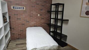 Relax in a serene space with a brick wall, a cozy bench, and a shelving unit for unwinding.