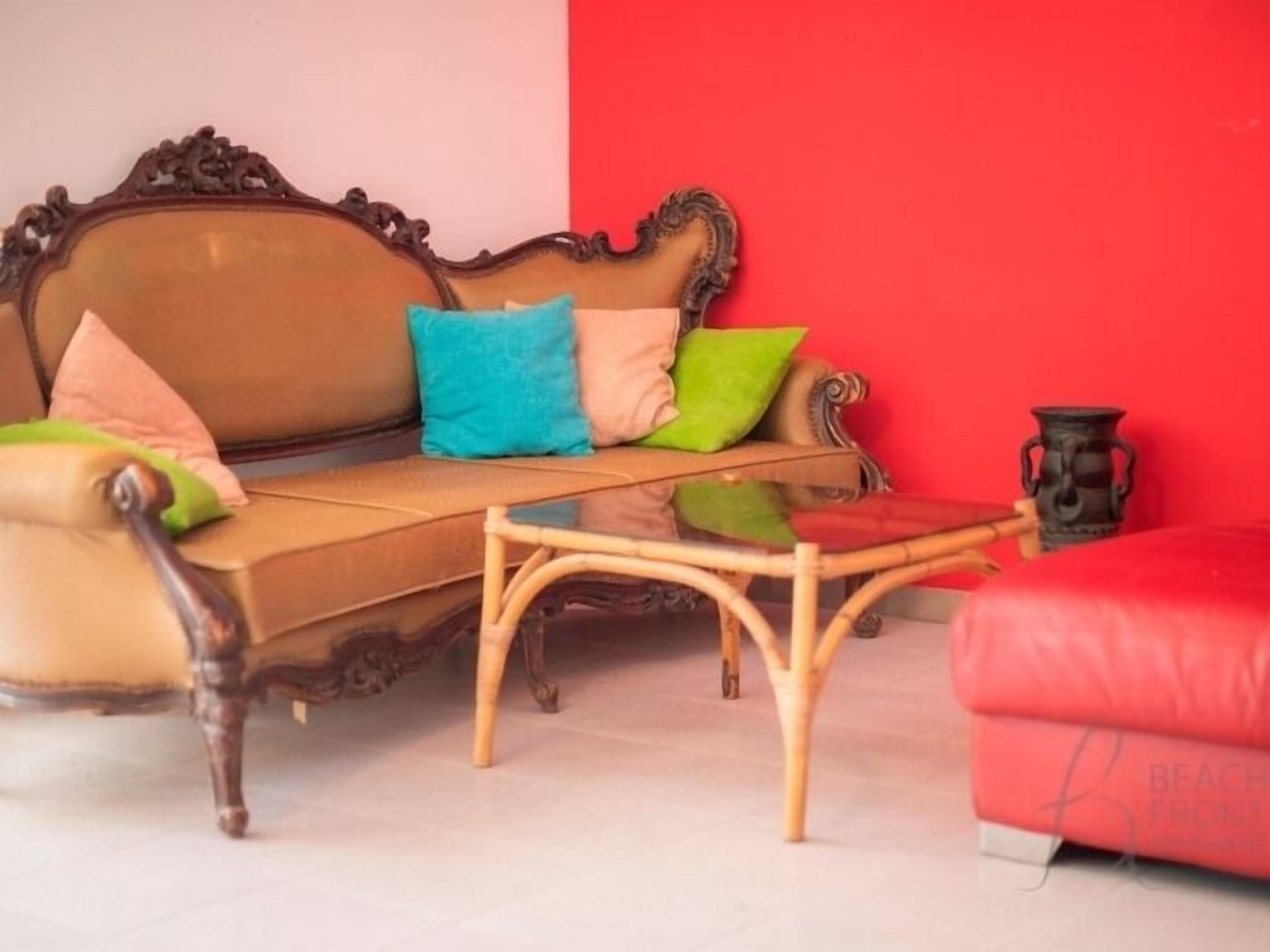 Une pièce avec un canapé marron, une table basse en verre et un mur rouge.