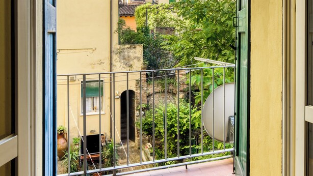 Ein Balkon mit Metallgeländer, Blick auf benachbarte Gebäude und einen klaren Himmel.