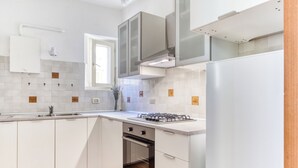 Eine moderne Küche mit weißen Schränken, einem Einbauofen, einem Gasherd und einem Edelstahl-Kühlschrank.