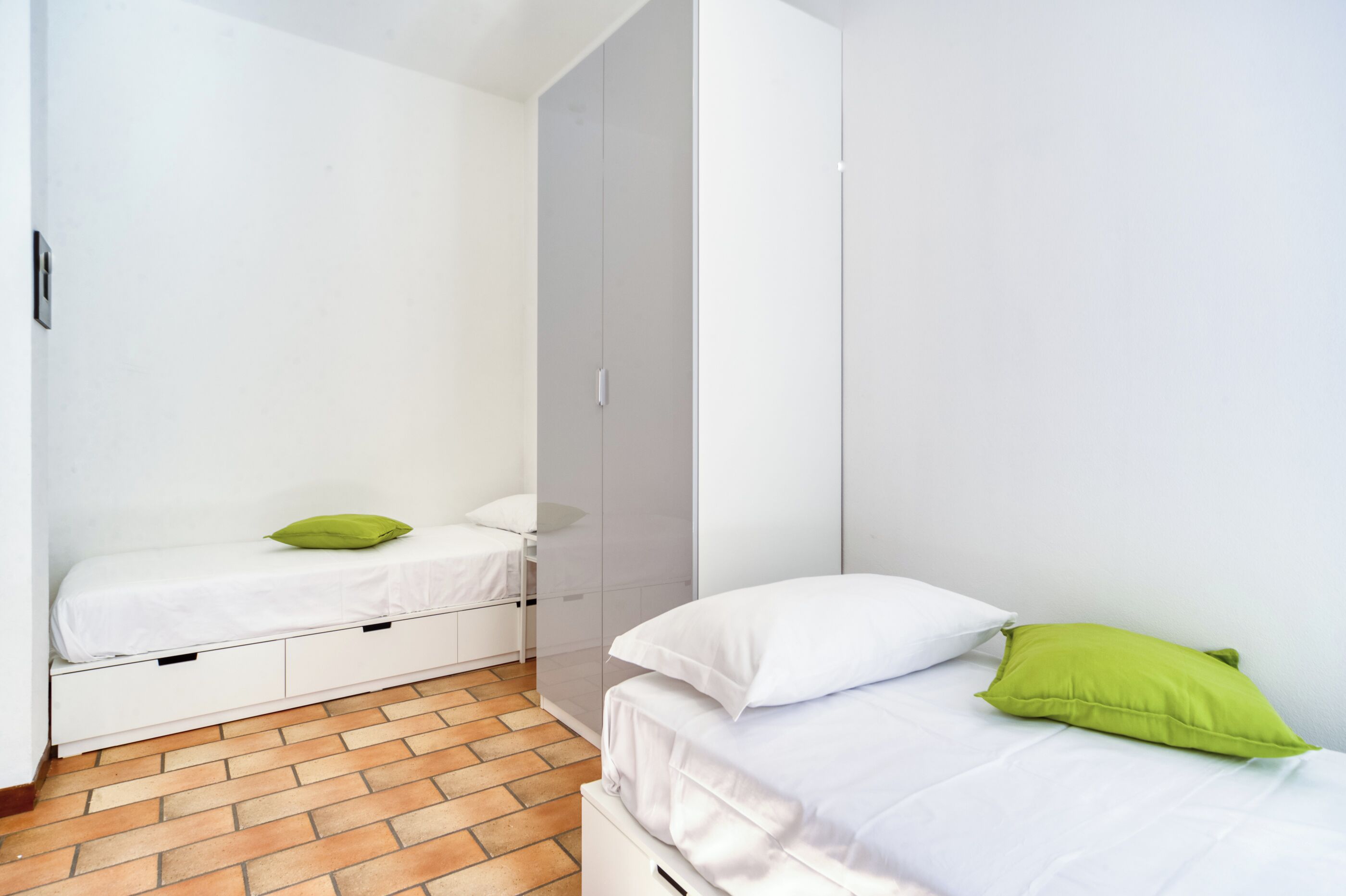 Un dormitorio pequeño y ordenado con una cama individual, una mesita de noche y un armario.