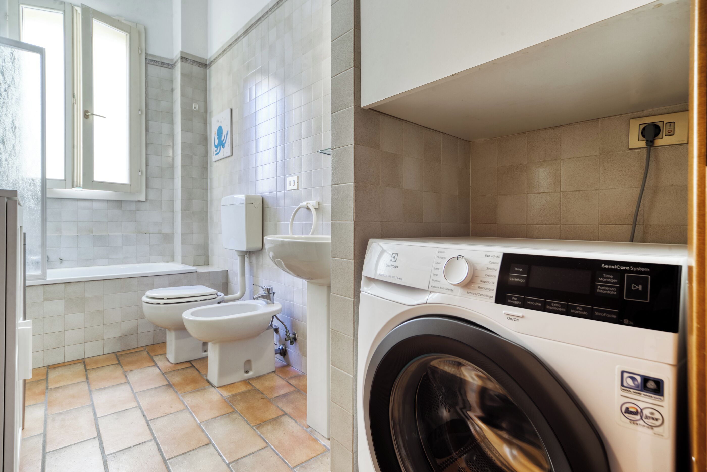 A bathroom with a toilet, bidet, and washing machine.