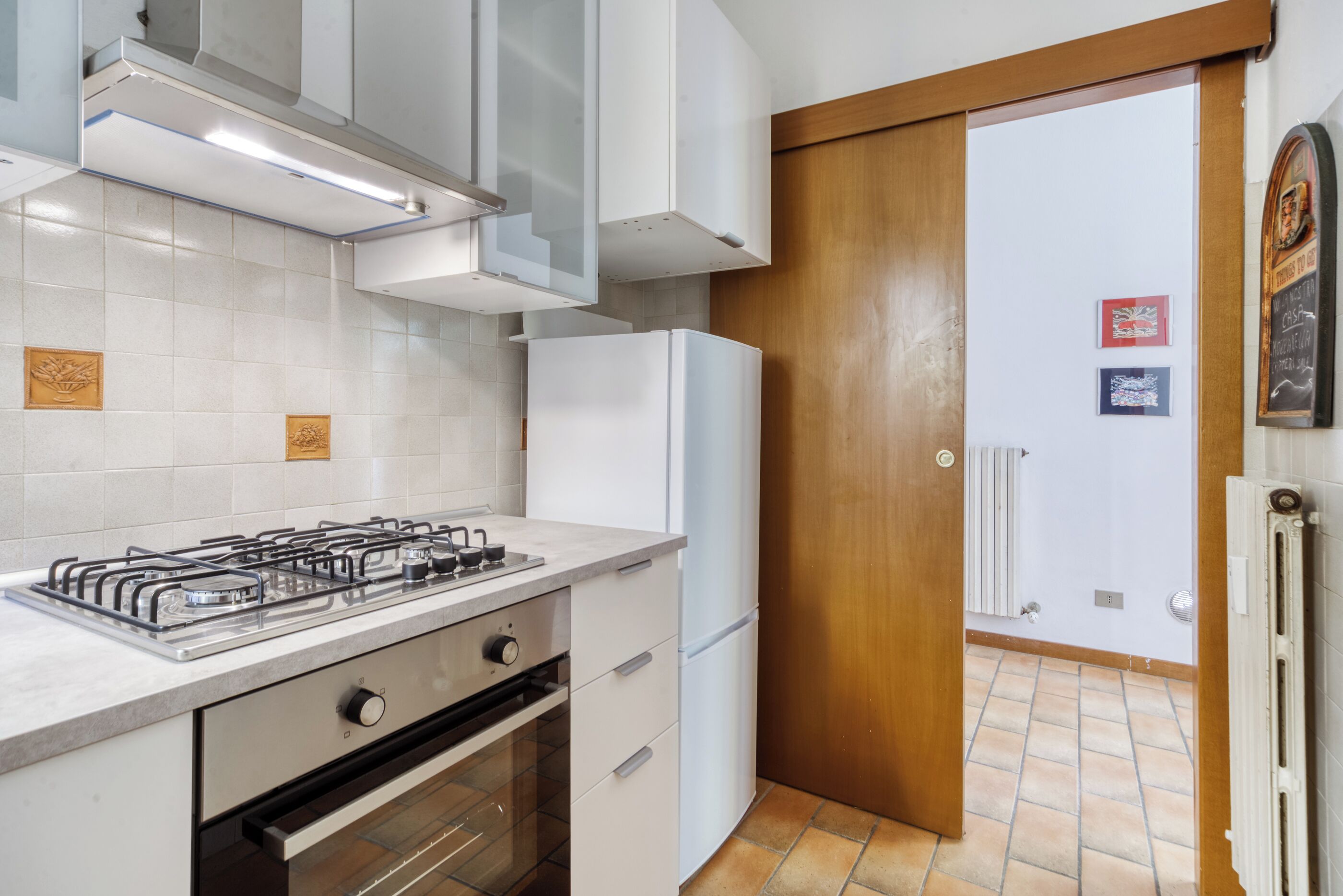 Una cocina moderna con gabinetes blancos, estufa a gas, horno y refrigerador.