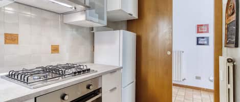 Una cocina moderna con gabinetes blancos, estufa a gas, horno y refrigerador.