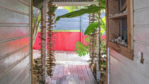 A narrow wooden pathway leading to a covered area with a red wall and a wooden shelf with decorative items. - Complete relaxation at Villa Lakaz with its spacious terrace and private pool. (Le Moule)