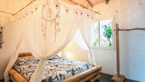 A room with a bed under a canopy, a window with a view, and a wooden floor. - Complete relaxation at Villa Lakaz with its spacious terrace and private pool. (Le Moule)