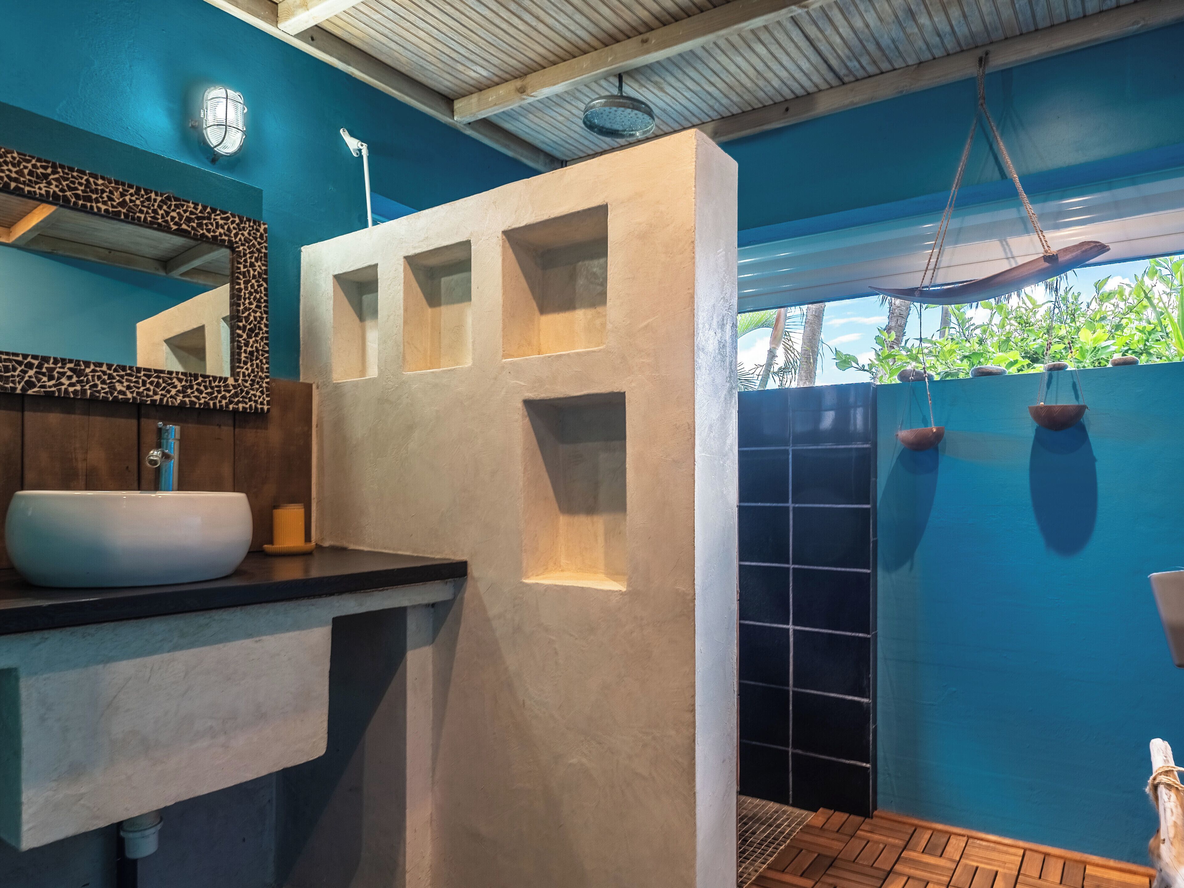 A bathroom with a white sink, a mirror with a giraffe pattern frame, and a blue tiled wall.