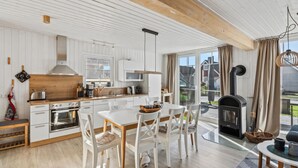 Una cocina moderna con armarios blancos, encimera de madera y un comedor con sillas blancas.