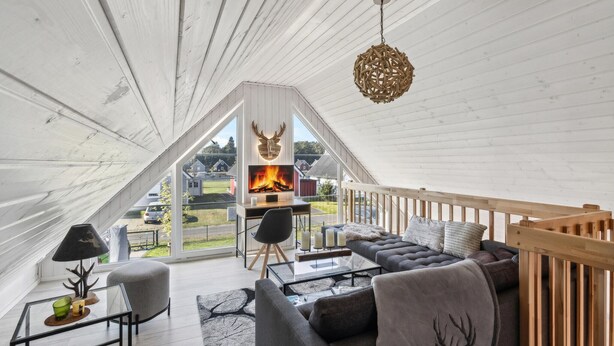 Un dormitorio loft moderno y acogedor con un ventanal grande, chimenea y una zona de estar confortable.