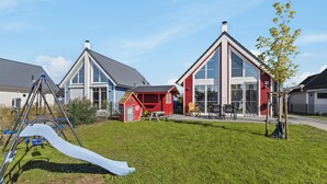 Zona residencial con casas modernas, un parque infantil y cielo despejado.