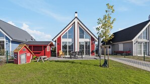 Zona residencial con una casa roja que tiene un gran ventanal y una chimenea blanca.