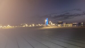A wide, empty pedestrian walkway with parallel lines, leading to a brightly lit area with a blue-lit structure. - 1 Bedroom Private vacation home in La Seyne-sur-Mer (La Seyne-sur-Mer)