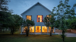 A two-story house with a stone foundation, large windows, and a front porch.