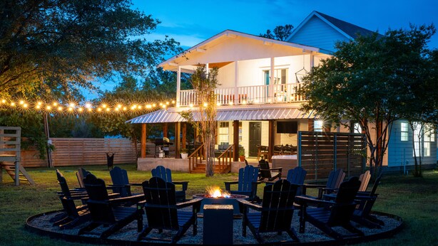 A house with a deck, outdoor seating area with chairs, and a fire pit.