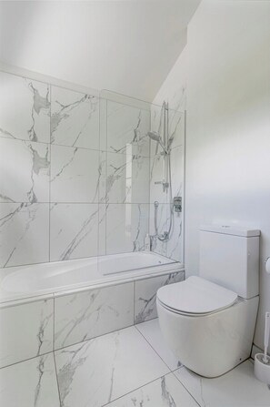 Bathroom features a bathtub, toilet, and shower area.