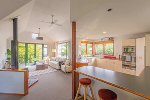 Relax in this open-plan living space with a sofa set, coffee table, and dining area, featuring a stove, microwave, and cabinets.