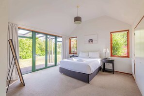 Relax in this serene bedroom with a large bed and sliding door leading to an outdoor area.