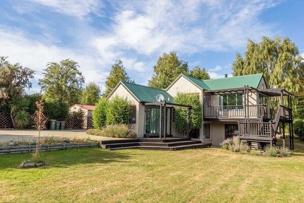Relax on the covered porch, surrounded by a lush lawn and trees.