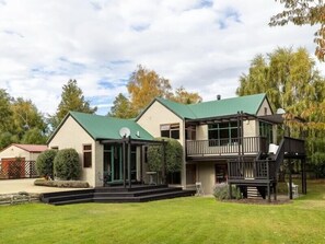 Enjoy the serene atmosphere of this two-story building with a central entrance and covered porch area, surrounded by a well-maintained lawn and trees.