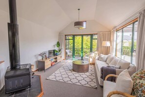 Relax in this spacious living area with a high ceiling, large window, and comfortable sofa.