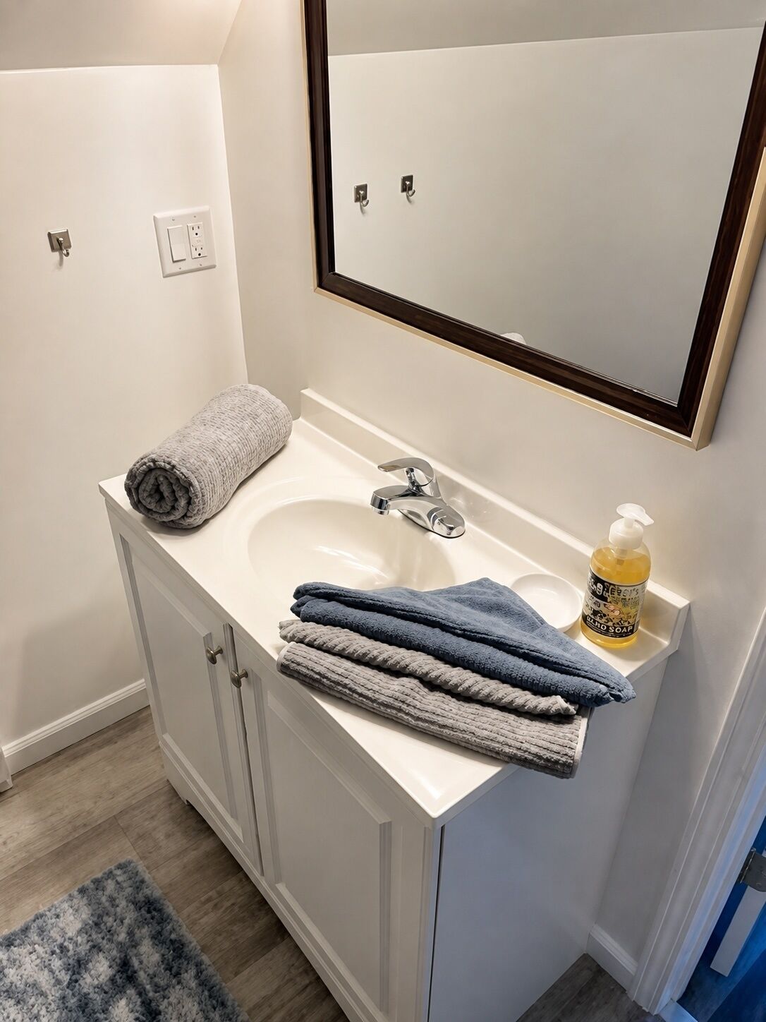 A bathroom with a white sink, a mirror, and a towel rack.