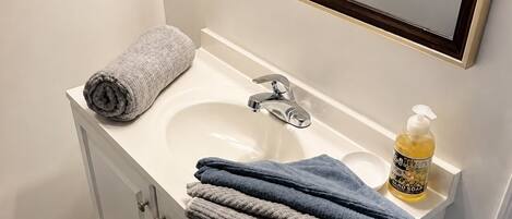A bathroom with a white sink, a mirror, and a towel rack.
