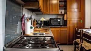 A kitchen with wooden cabinets, a gas stove, a microwave, and a sink. - LaCasaDeiNonni - Lakes&Relax (Varano Borghi)